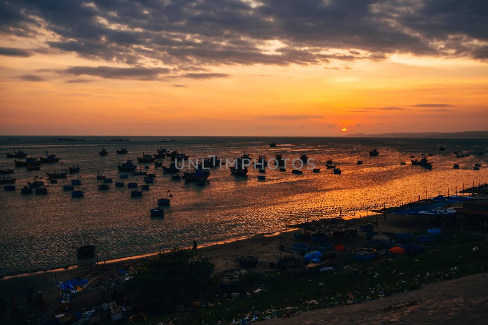silhouettes of traditional Vietnamese boats in Mui Ne fishing village at sunset