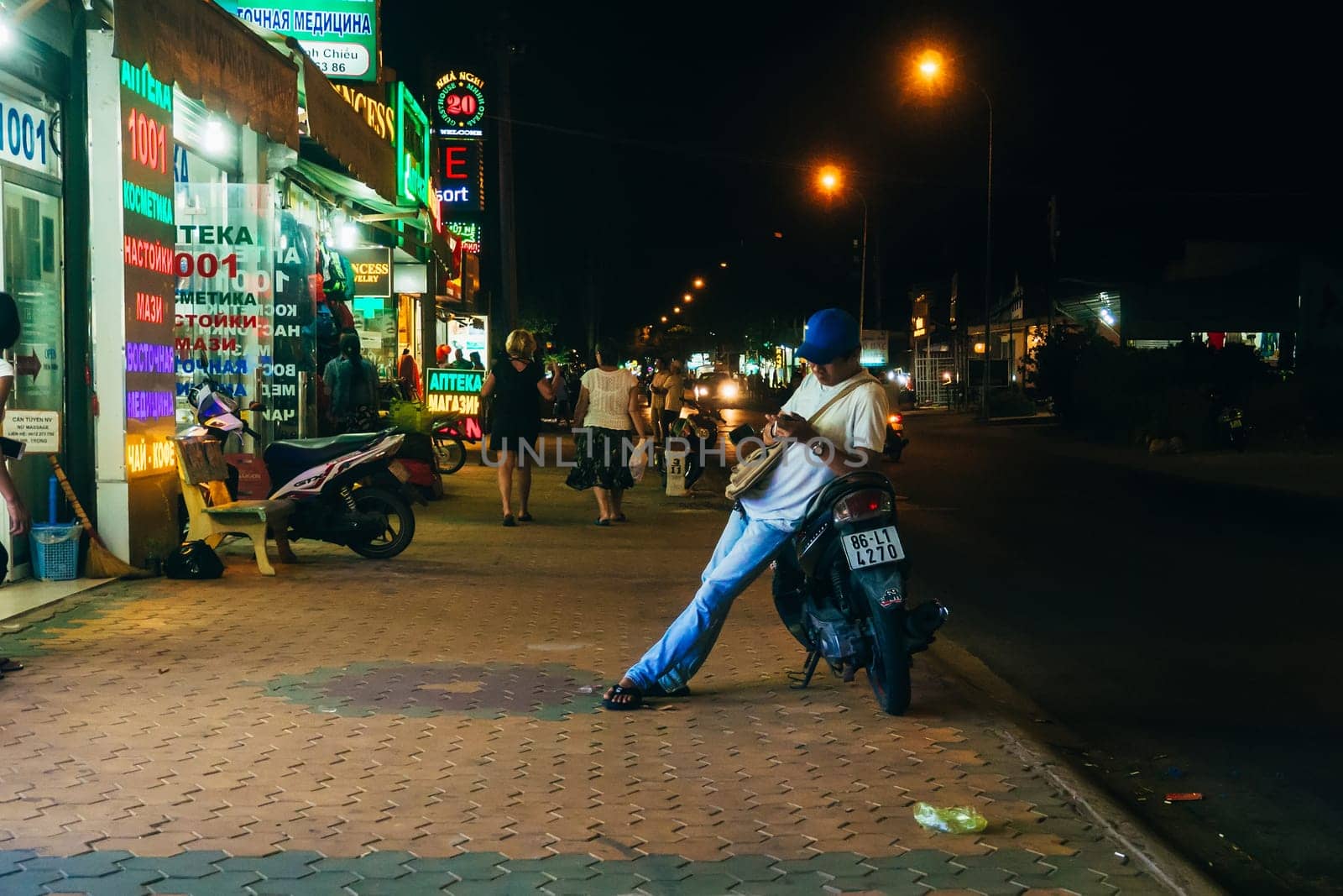 MUI NE, VIETNAM - CIRCA MARCH 2017: Night life on a busy street against the backdrop of many shops