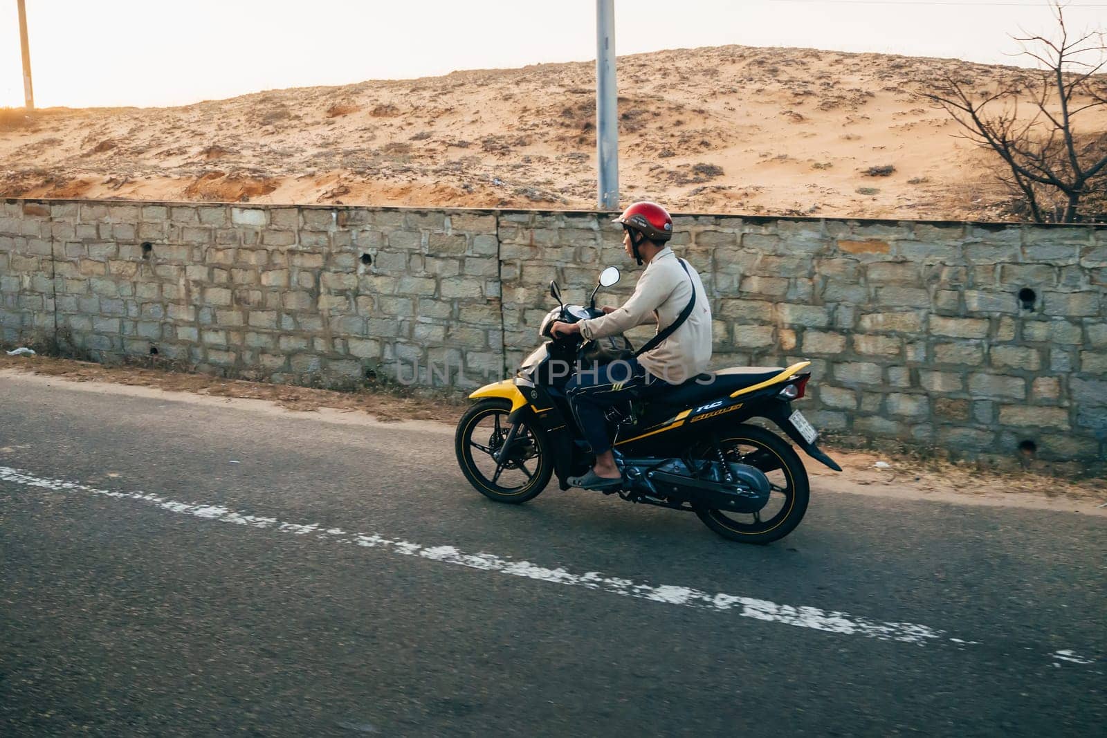 MUI NE, VIETNAM - CIRCA MARCH 2017: A man riding a motorbike on the road