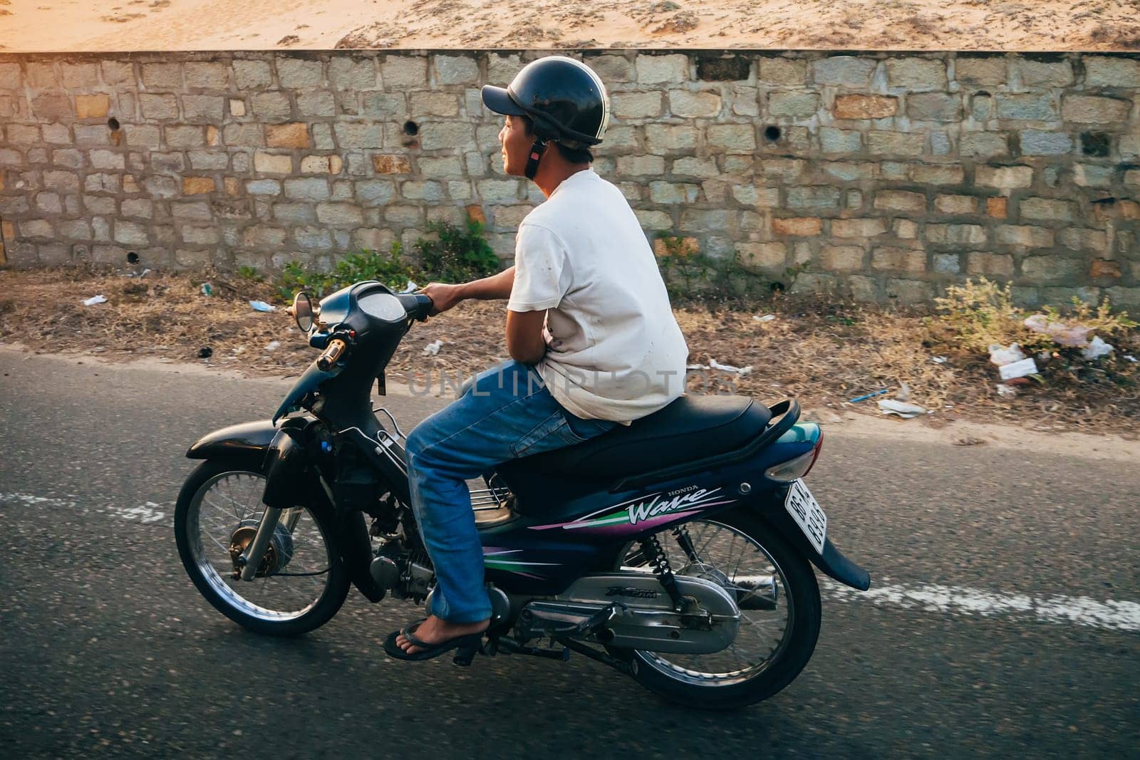 MUI NE, VIETNAM - CIRCA MARCH 2017: A man riding a motorbike on the road