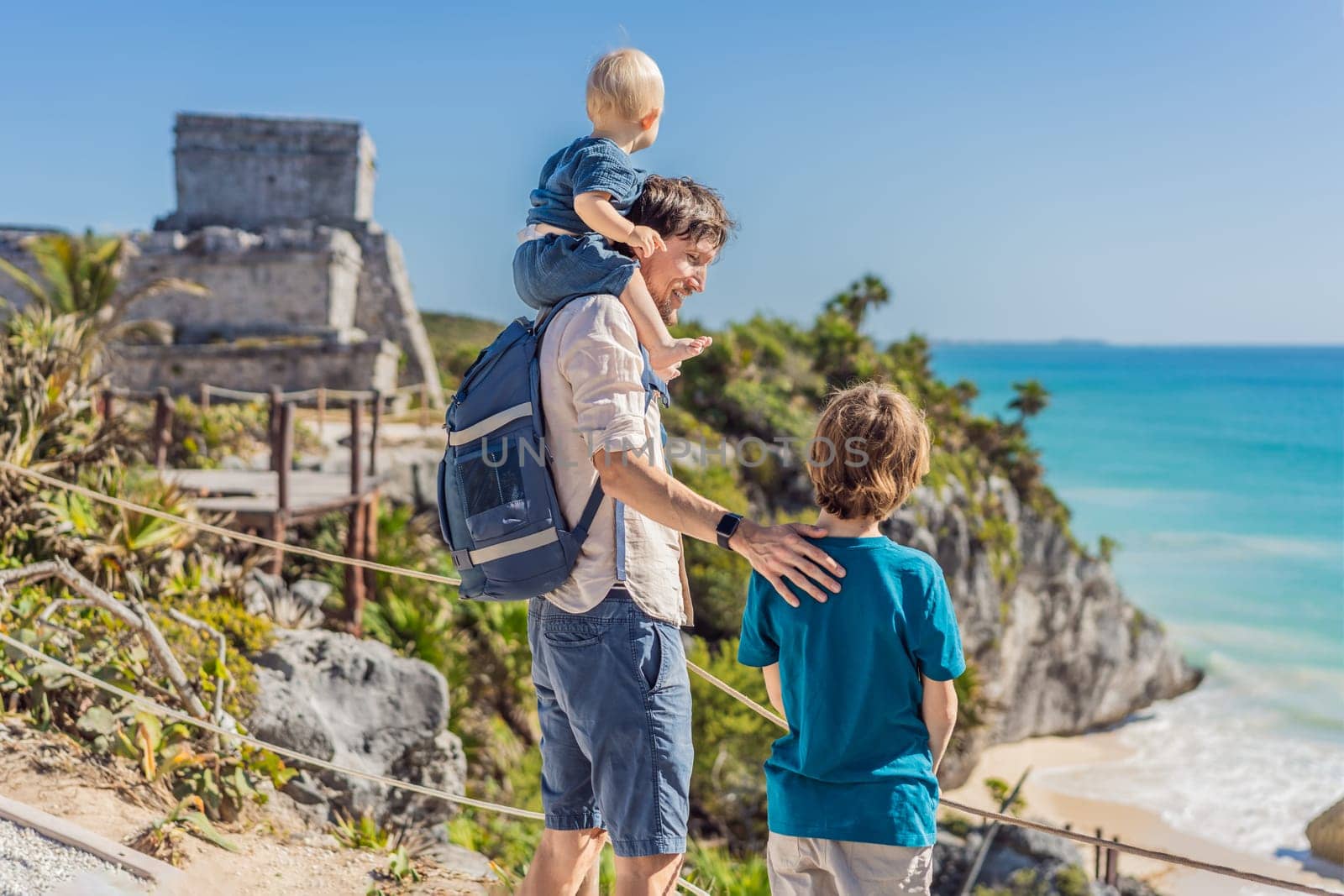Father and two sons tourists enjoying the view Pre-Columbian Mayan walled city of Tulum, Quintana Roo, Mexico, North America, Tulum, Mexico. El Castillo - castle the Mayan city of Tulum main temple by galitskaya