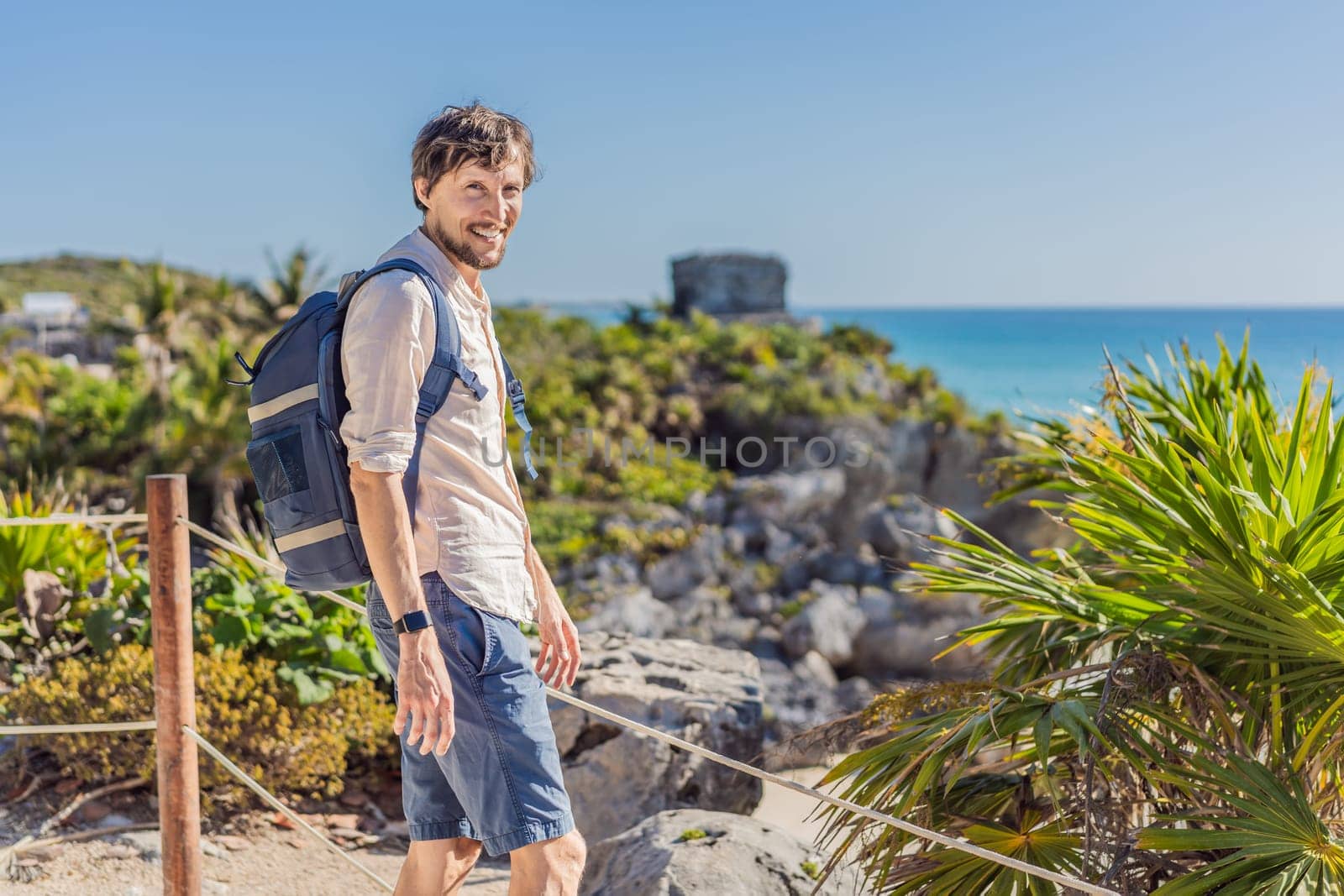 Man tourist enjoying the view Pre-Columbian Mayan walled city of Tulum, Quintana Roo, Mexico, North America, Tulum, Mexico. El Castillo - castle the Mayan city of Tulum main temple.