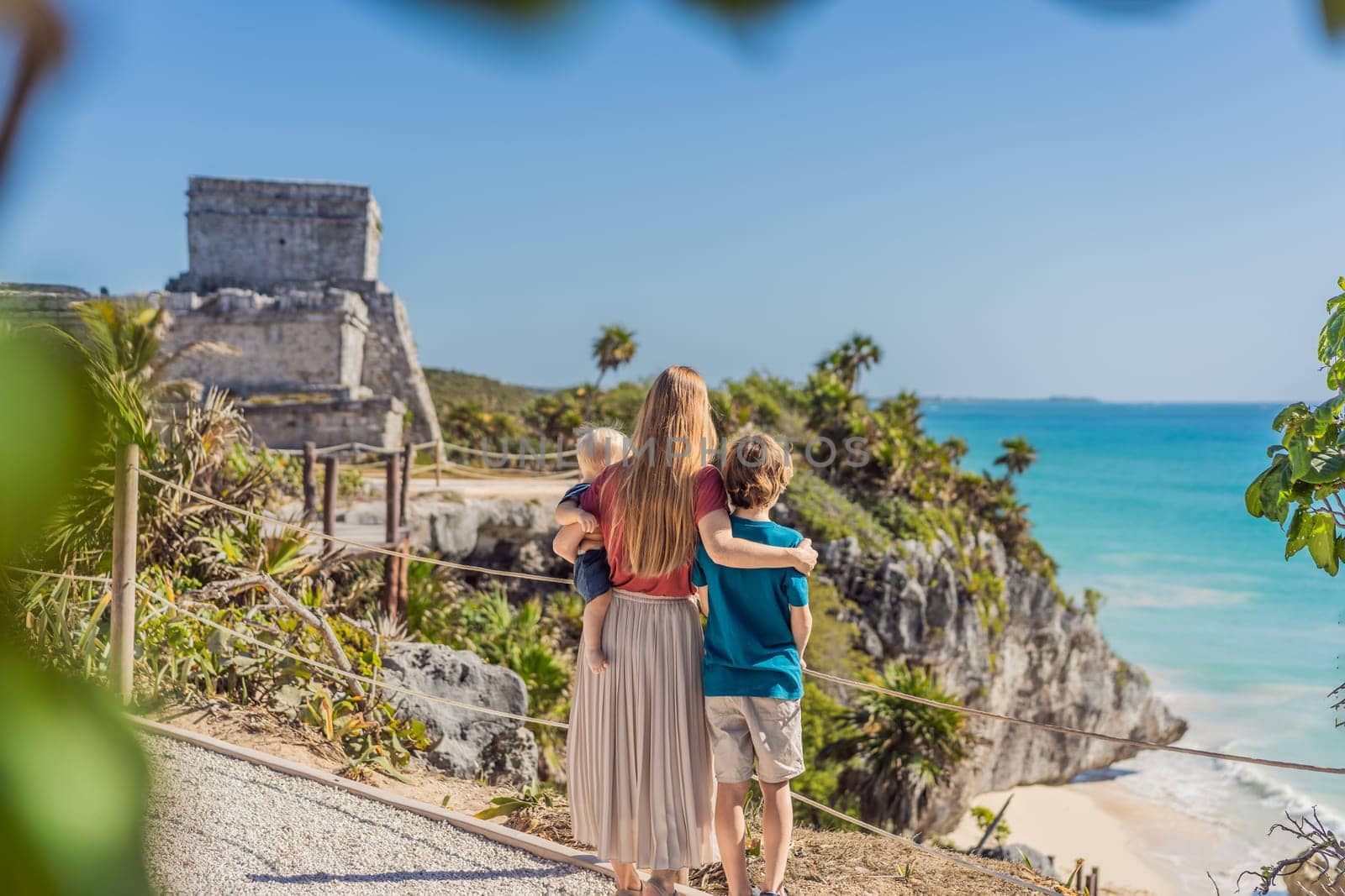 Mother and two sons tourists enjoying the view Pre-Columbian Mayan walled city of Tulum, Quintana Roo, Mexico, North America, Tulum, Mexico. El Castillo - castle the Mayan city of Tulum main temple by galitskaya