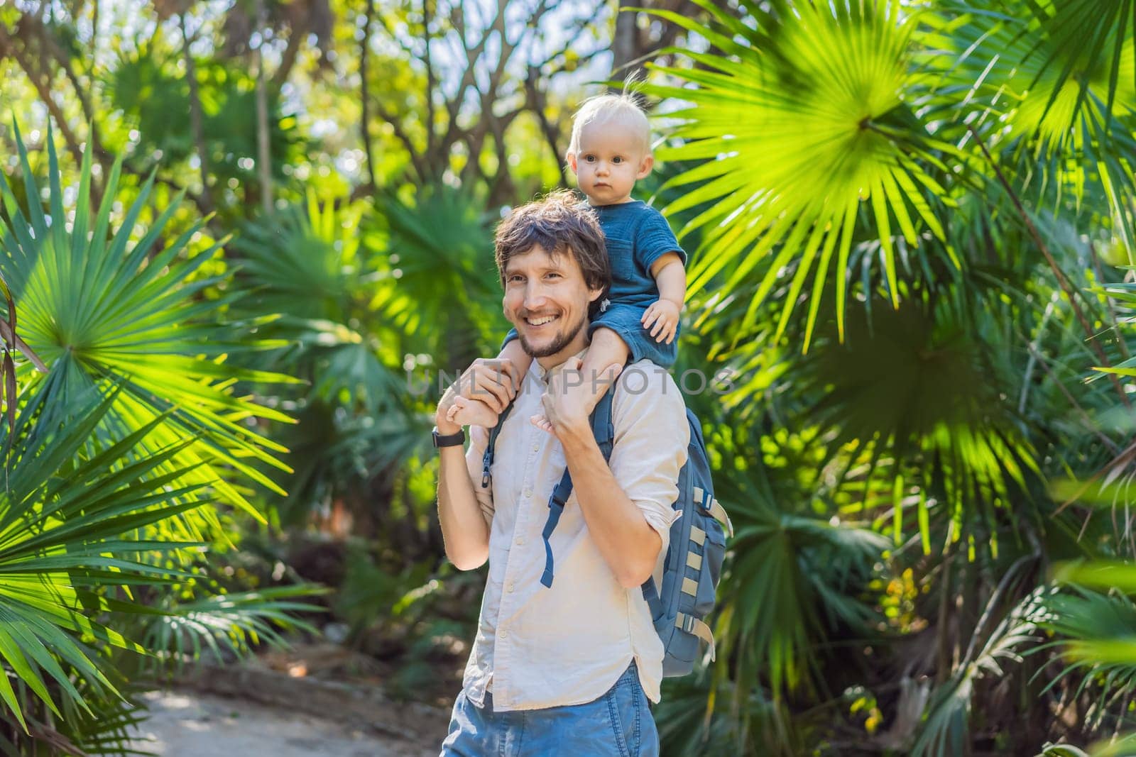 A man smiling while carrying a baby in the jungle, surrounded by lush vegetation by galitskaya