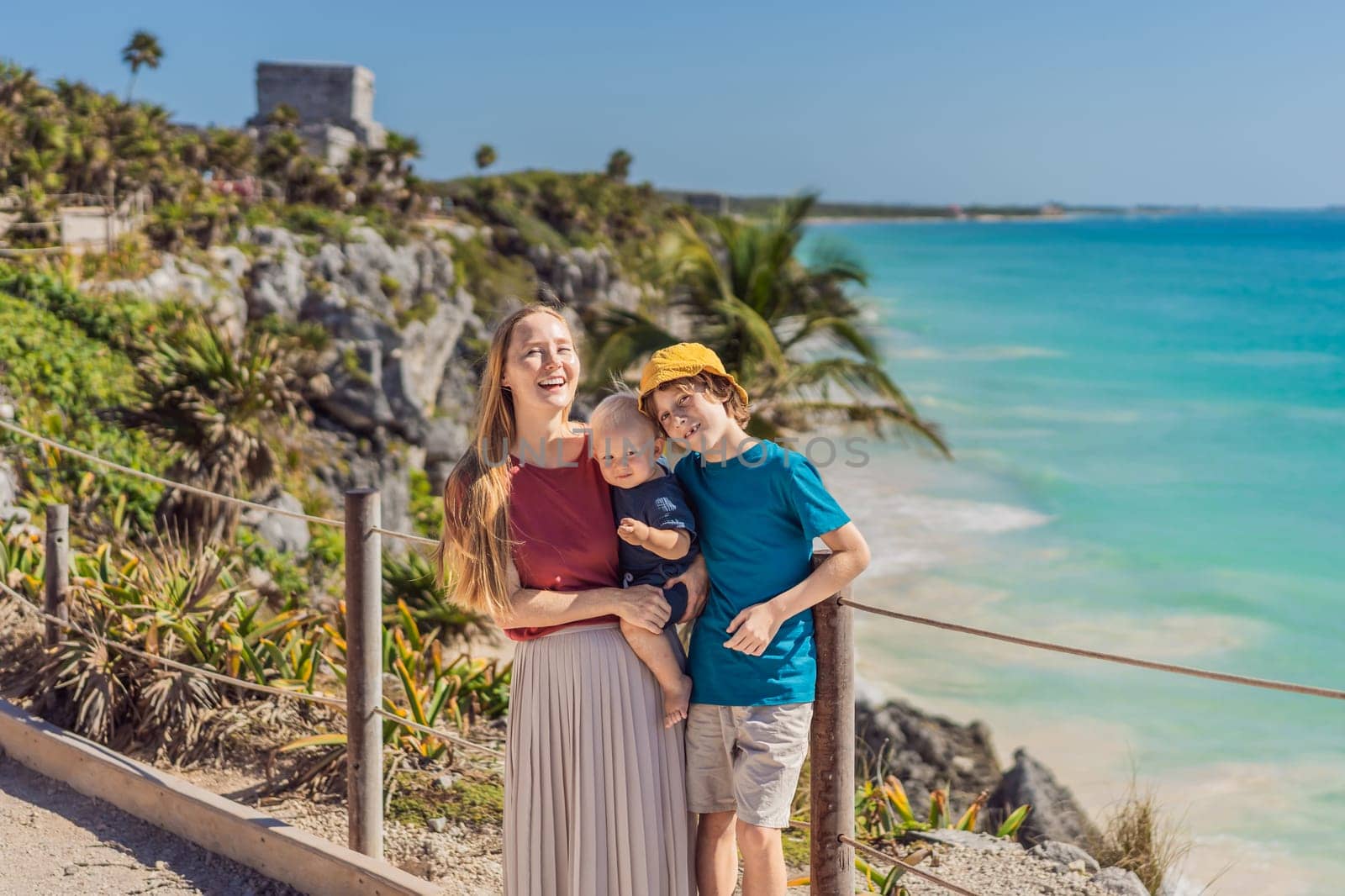 Mother and two sons tourists enjoying the view Pre-Columbian Mayan walled city of Tulum, Quintana Roo, Mexico, North America, Tulum, Mexico. El Castillo - castle the Mayan city of Tulum main temple.