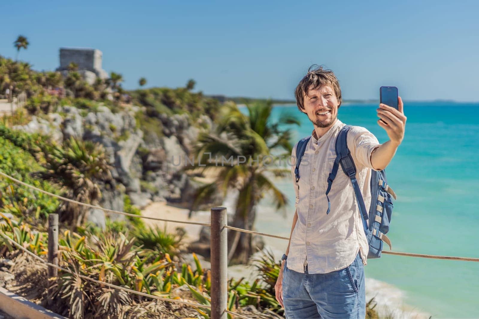 Man tourist enjoying the view Pre-Columbian Mayan walled city of Tulum, Quintana Roo, Mexico, North America, Tulum, Mexico. El Castillo - castle the Mayan city of Tulum main temple.