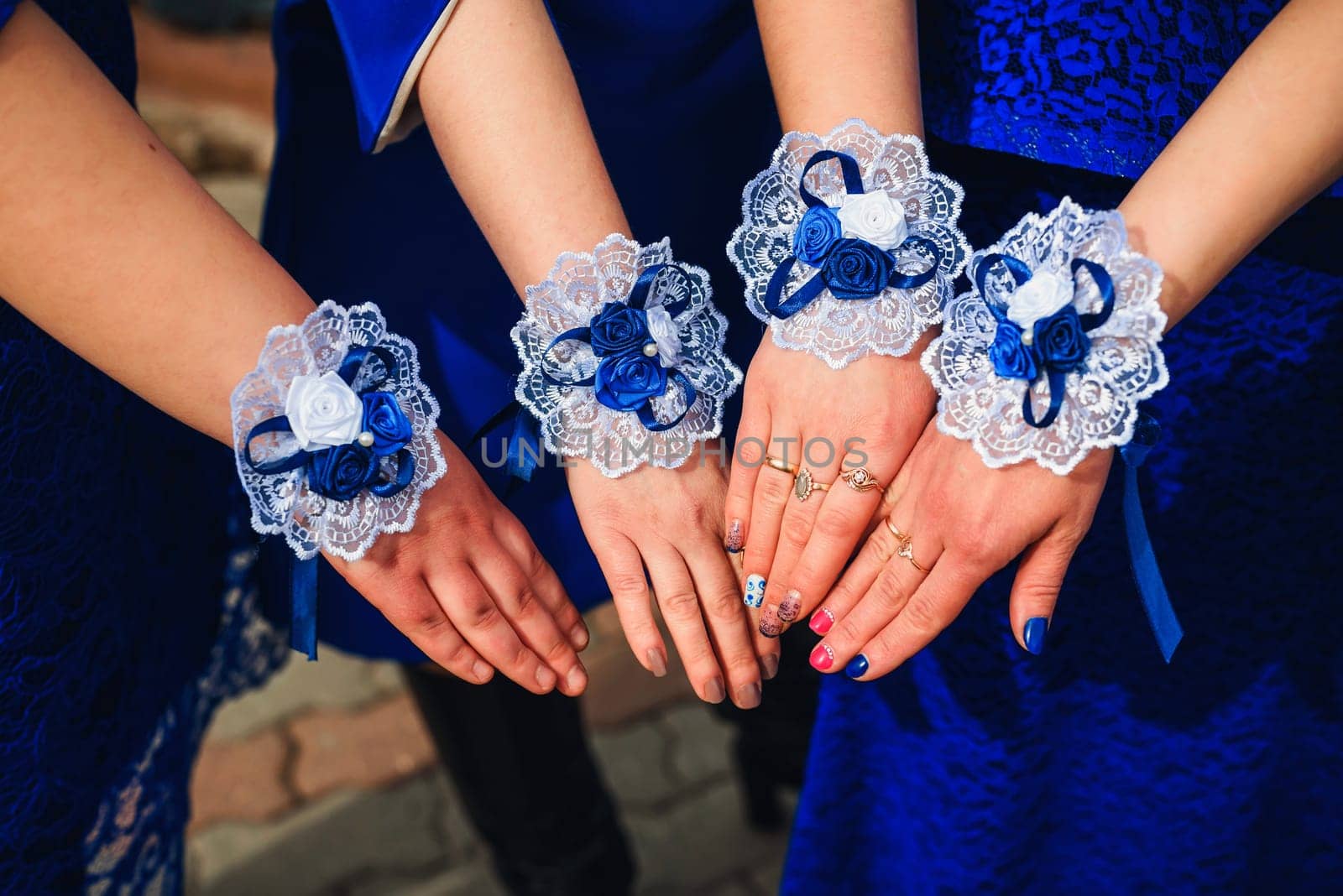 hands bridesmaids close-up in blue dresses with decorated bracelets