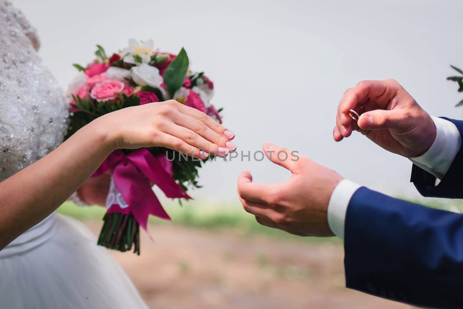 groom puts on the bride's hand wedding gold ring closeup
