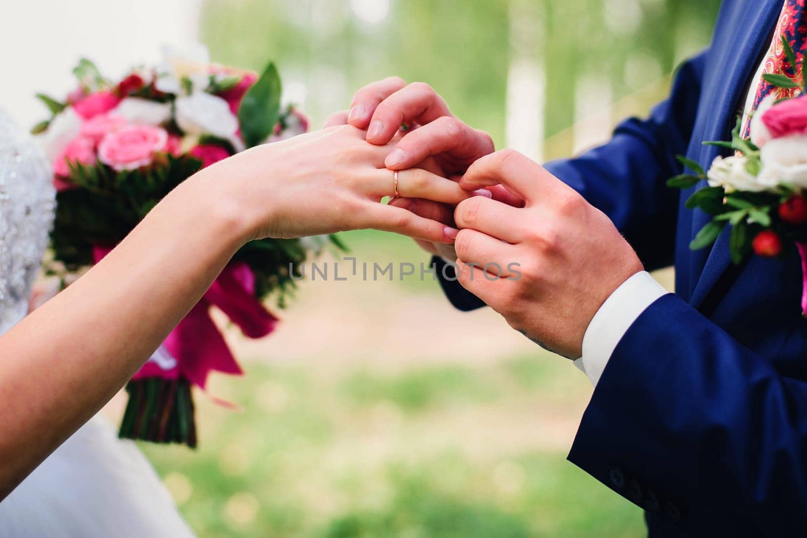 groom puts a wedding ring on the bride's finger at the wedding ceremony