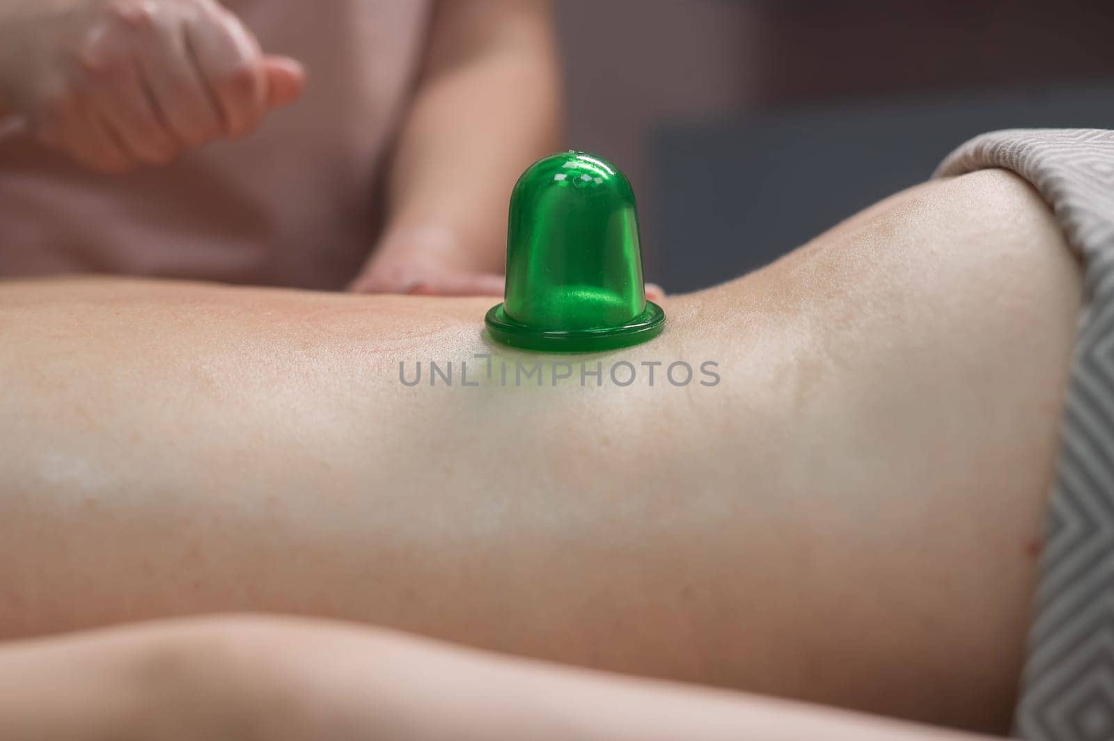 A woman undergoes an anti-cellulite massage procedure using a vacuum jar. Close-up of the lower back