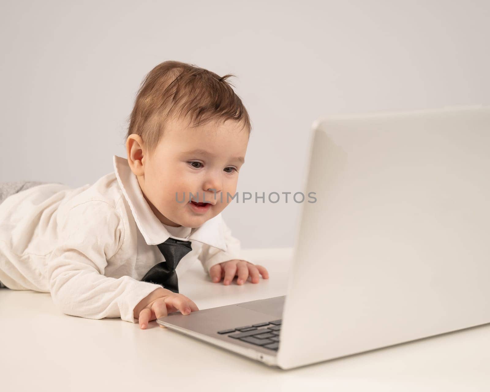 Cute baby boy in a tie working at a laptop