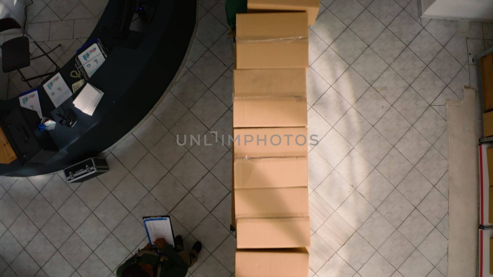 Top down view of warehouse chief supply chain officer examining cardboard box parcels in parallel, comparing findings. Depository staff members making sure stocks and inventory are well organized