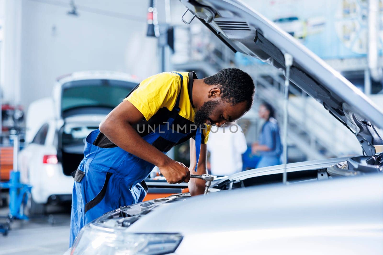 Garage engineer examines car brakes by DCStudio