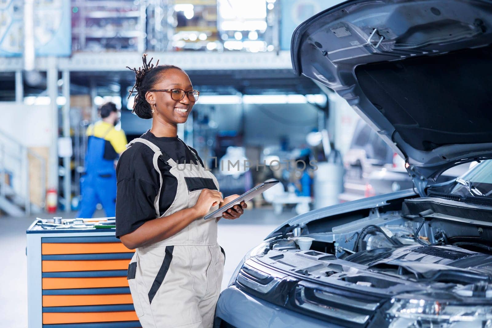 Portrait of proud BIPOC serviceman holding tablet in auto repair shop tasked with changing cars oil. Skilled woman in garage ready to start doing checkups on vehicles in garage workspace