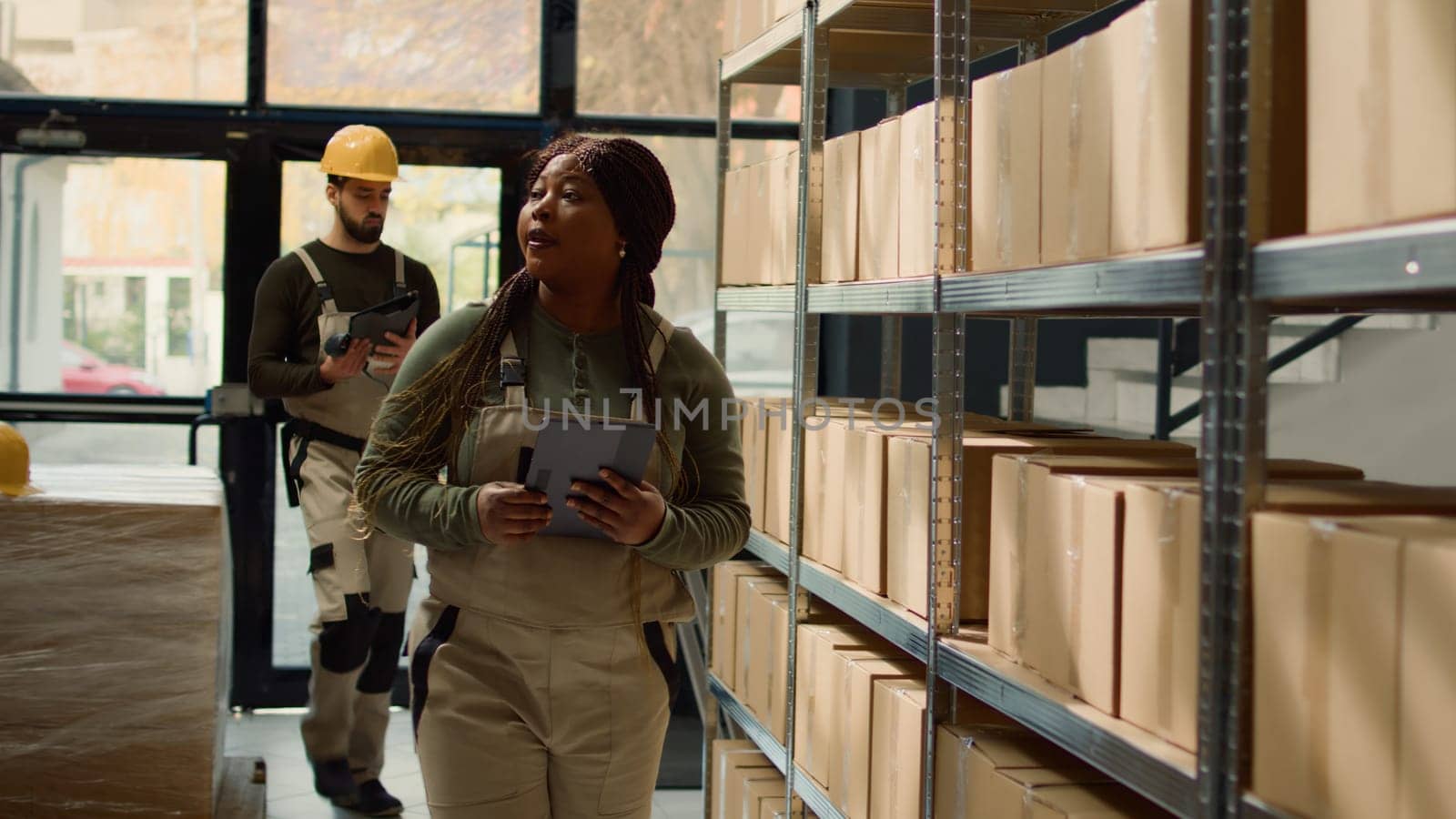 Revealing shot of woman in warehouse inputing updated products info on online shopping website using tablet, walking through retail storage hub aisles checking labels on wares