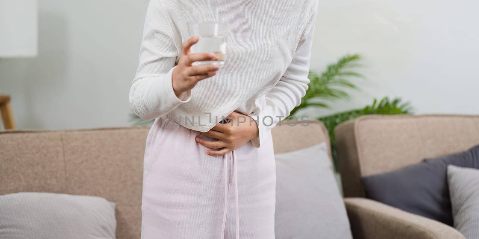 asian woman suffering from stomach ache, undergoing belly pain and discomfort, suffer from menstruation.