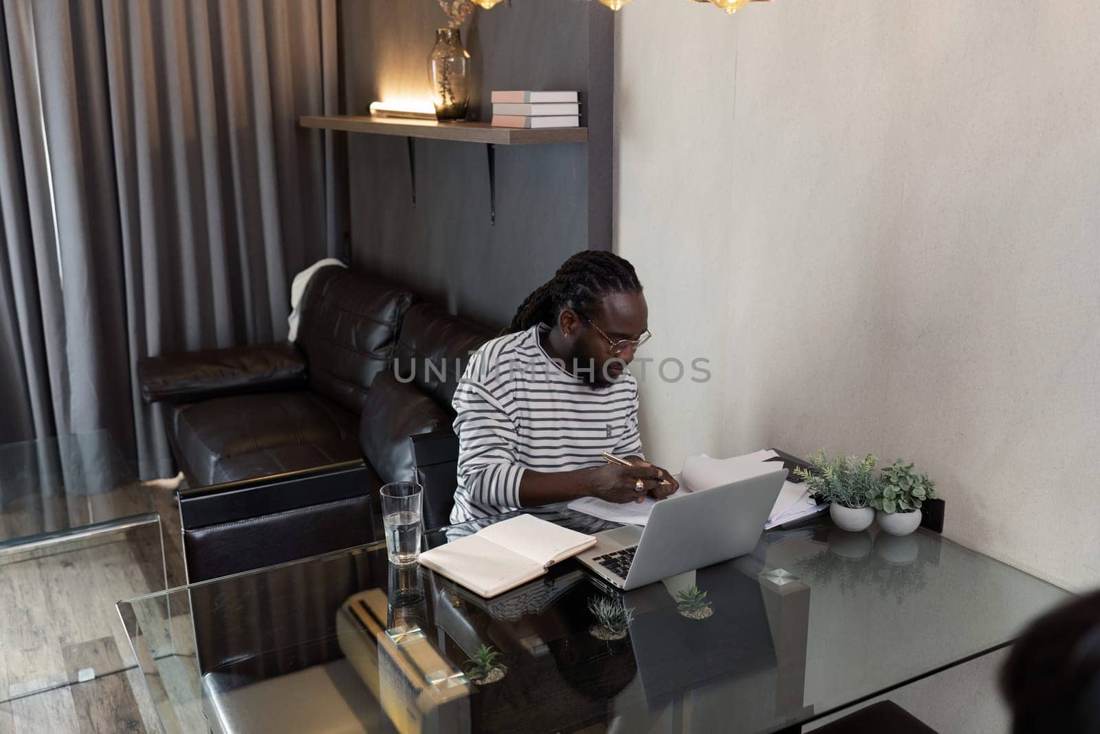 Young African American business man working with laptop and mobile on desk at home. work from home concept.