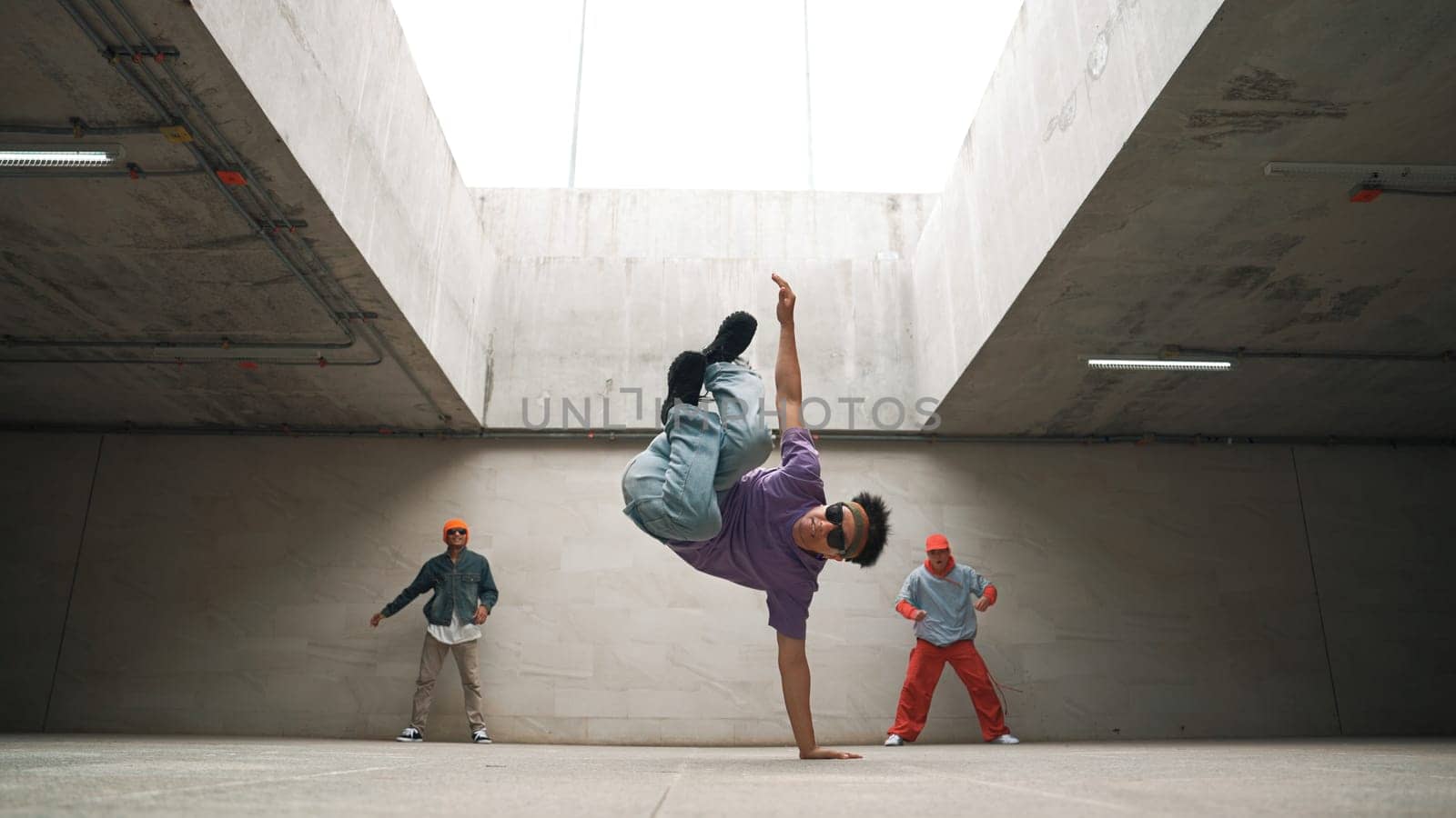 Group of stylish hipster perform dancing together in building. Happy break dancer enjoy moving to hip hop music with freestyle dance surrounded by street dancer team. Outdoor sport 2024. Sprightly.