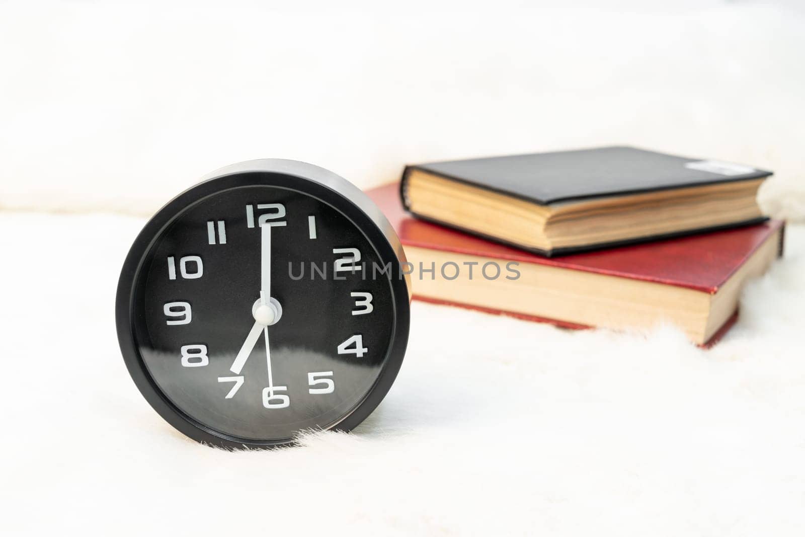 Close up Black alarm clock and book stacked on table