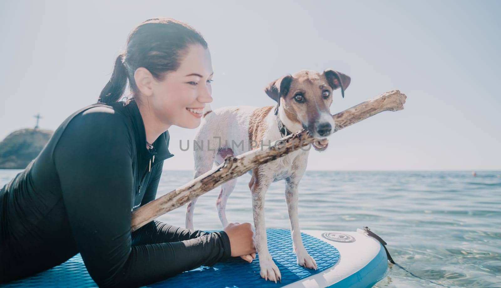 Sea woman sup. Silhouette of happy positive young woman with her dog, surfing on SUP board through calm water surface. Idyllic sunset. Active lifestyle at sea or river. Summer vacation with pets. by panophotograph