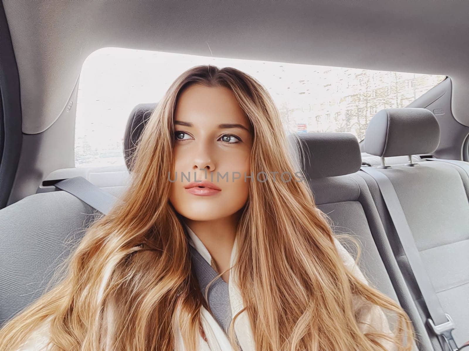 Young woman with long hair, wavy hairstyle in the car or taxi cab as passenger, exploring the city, transport and travel by Anneleven