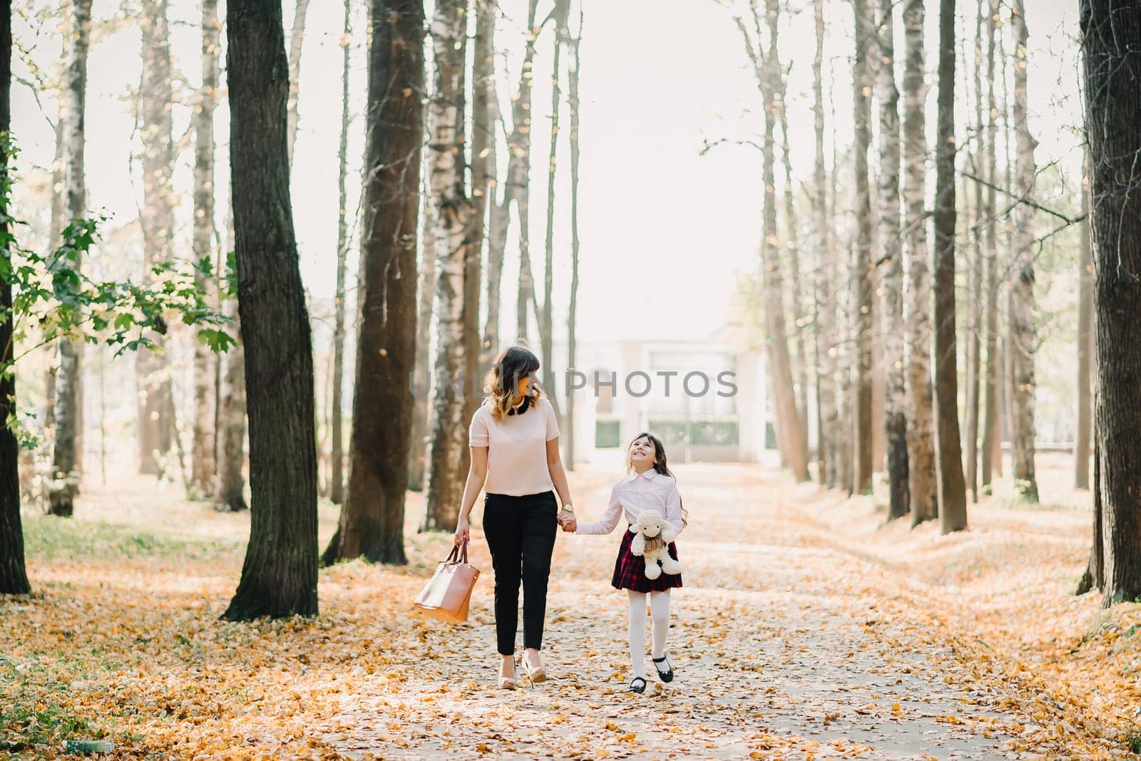 happy mother and daughter walking in the Park in autumn