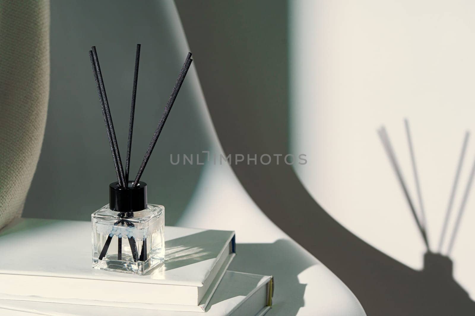 Liquid home perfume in glass diffuser with sticks on chair close up