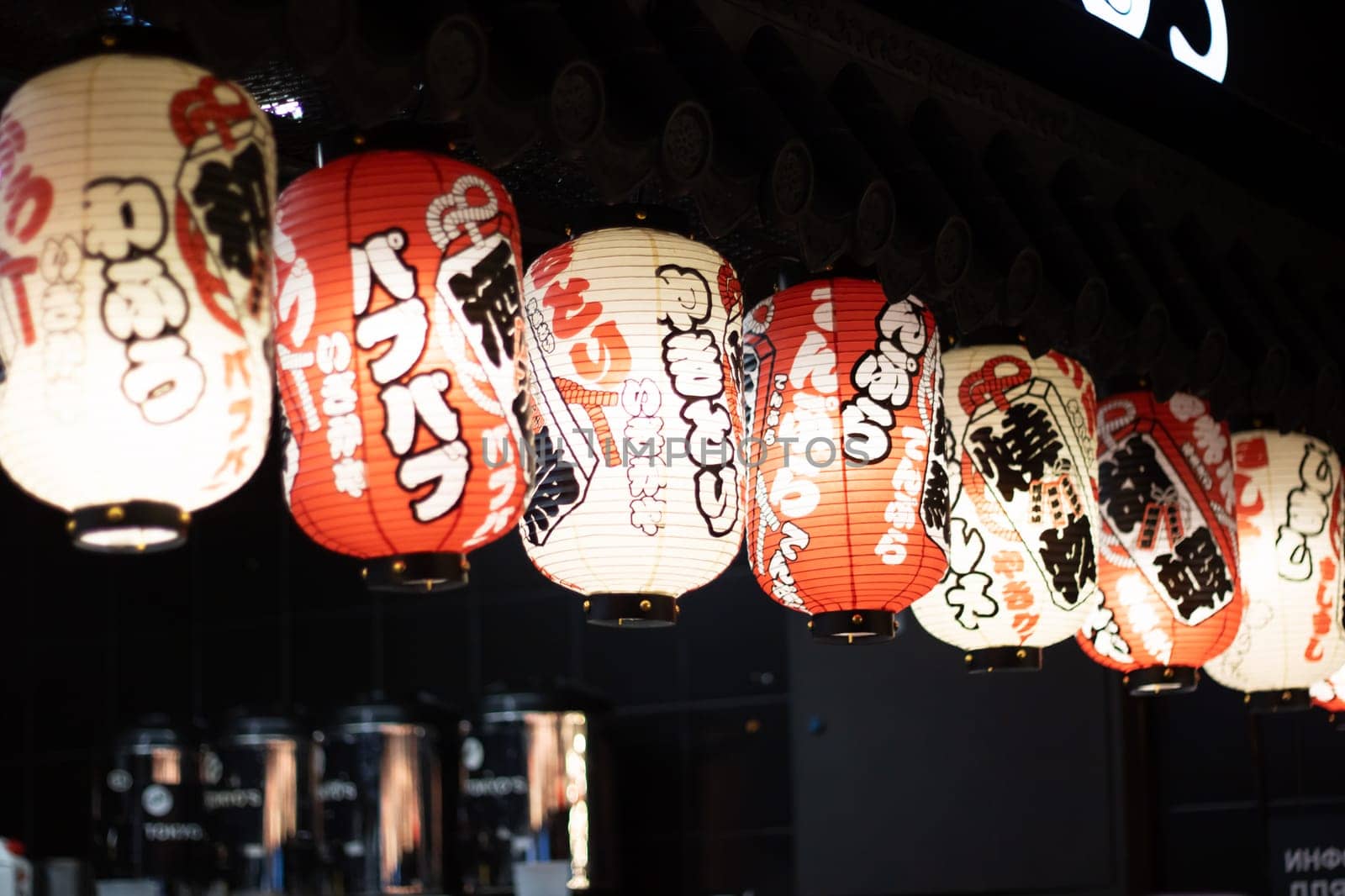 The restaurant is adorned with a row of colorful lanterns hanging from the ceiling, creating a vibrant atmosphere in the room