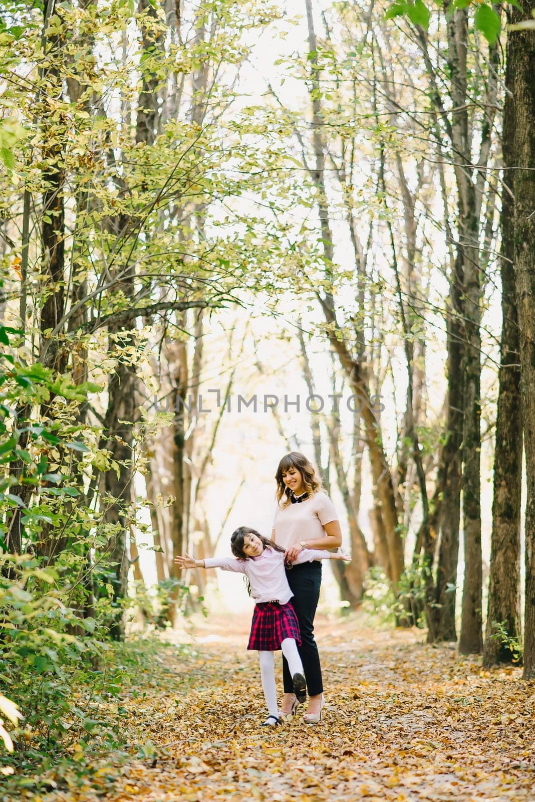happy mom and daughter fall in the Park playing and laughing