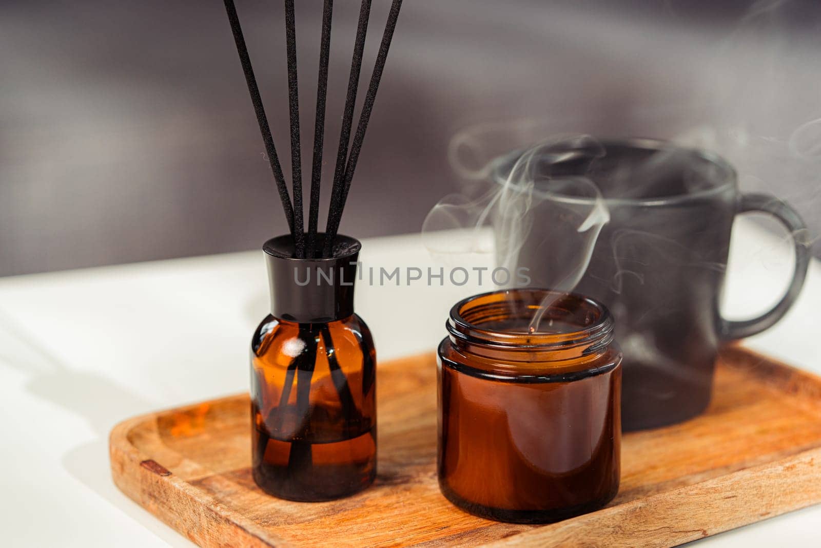Aromatic reed freshener and candle on table in room close up