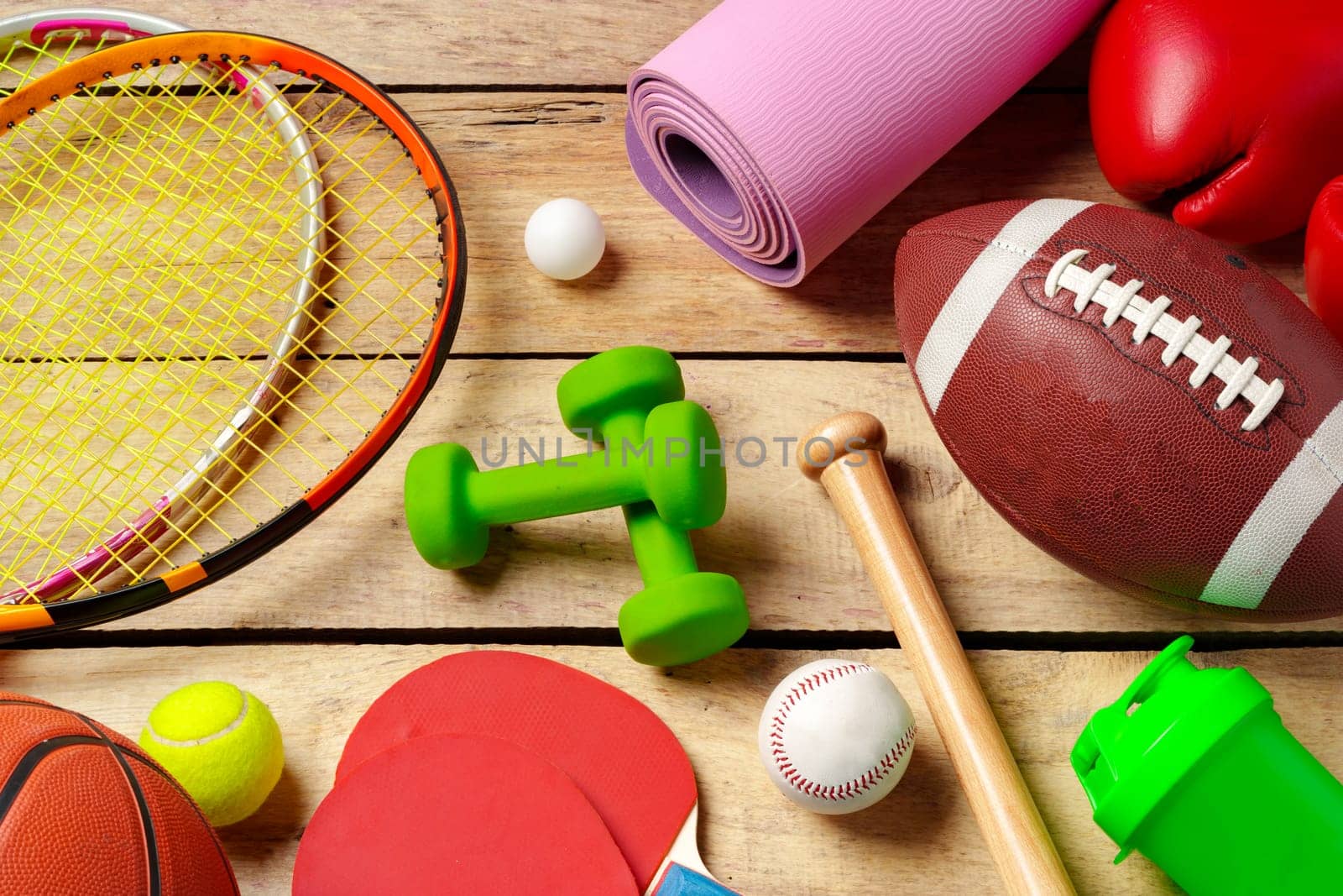 Different sports equipment on wooden background top view by Fabrikasimf