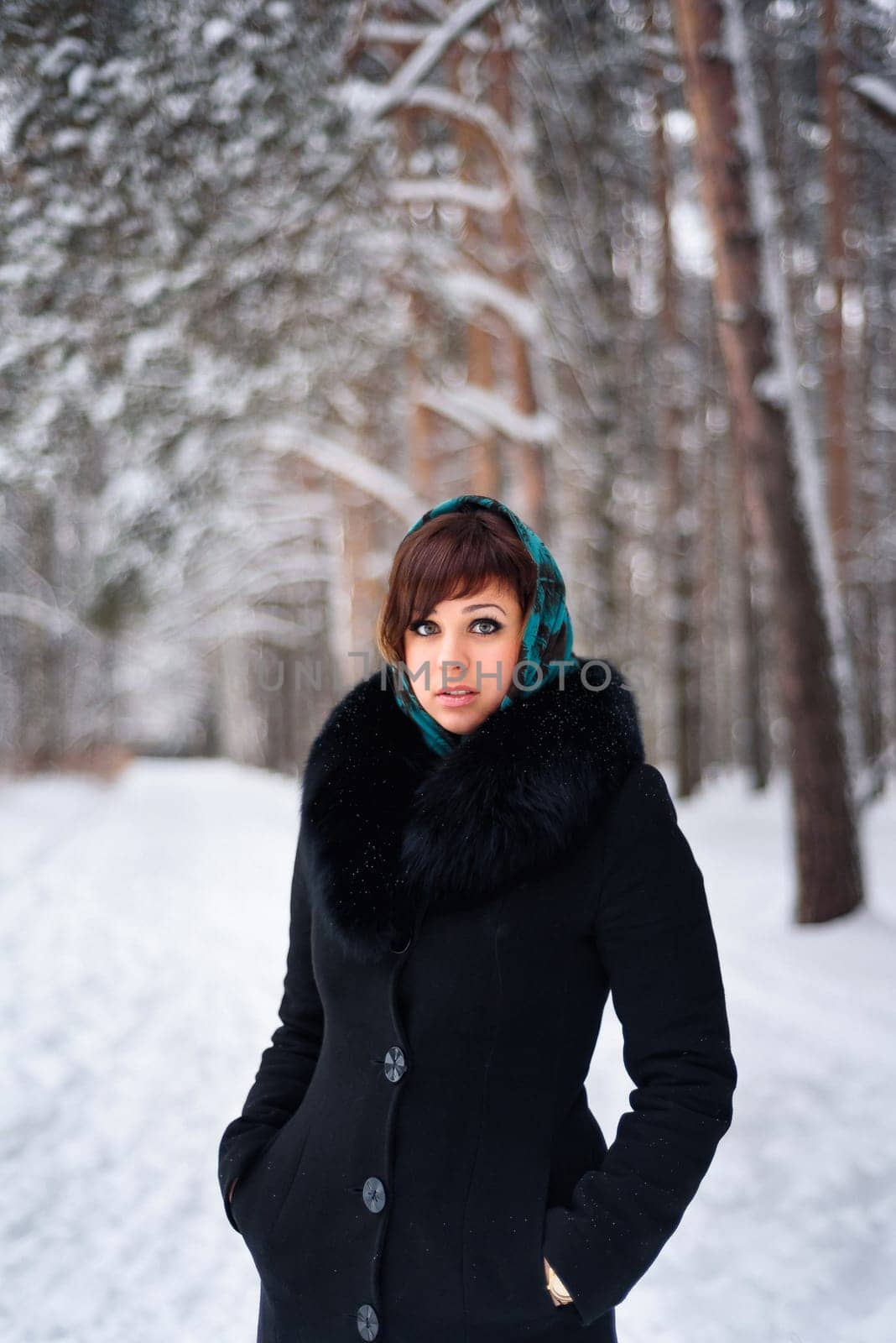 Russian girl in coat and scarf in cold winter in the woods