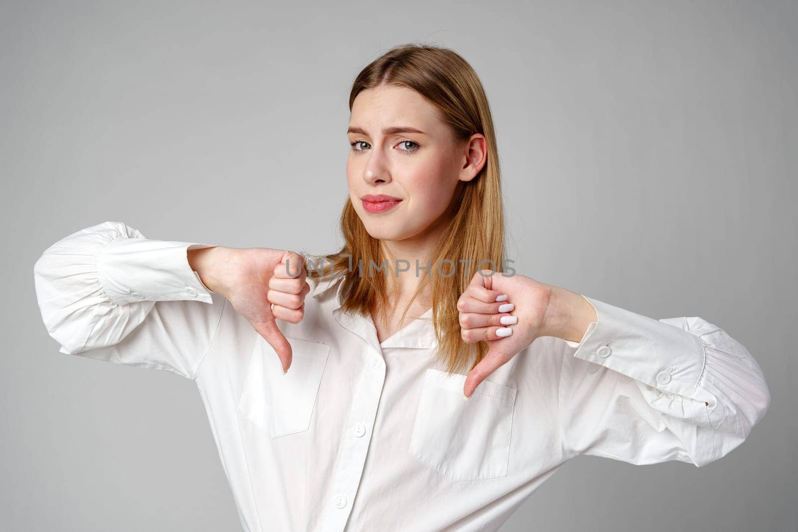 Young Woman in White Shirt Pointing Finger Down Dislike by Fabrikasimf