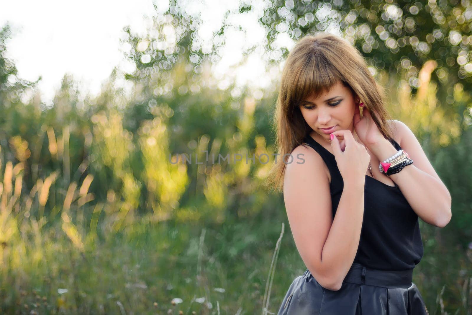 young Caucasian girl posing in summer at sunset in the field