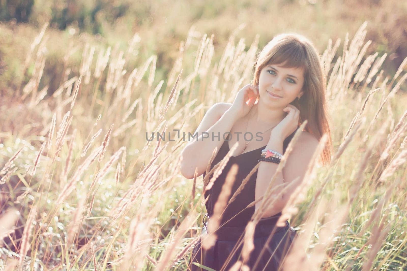 young Caucasian girl posing in summer at sunset in the field