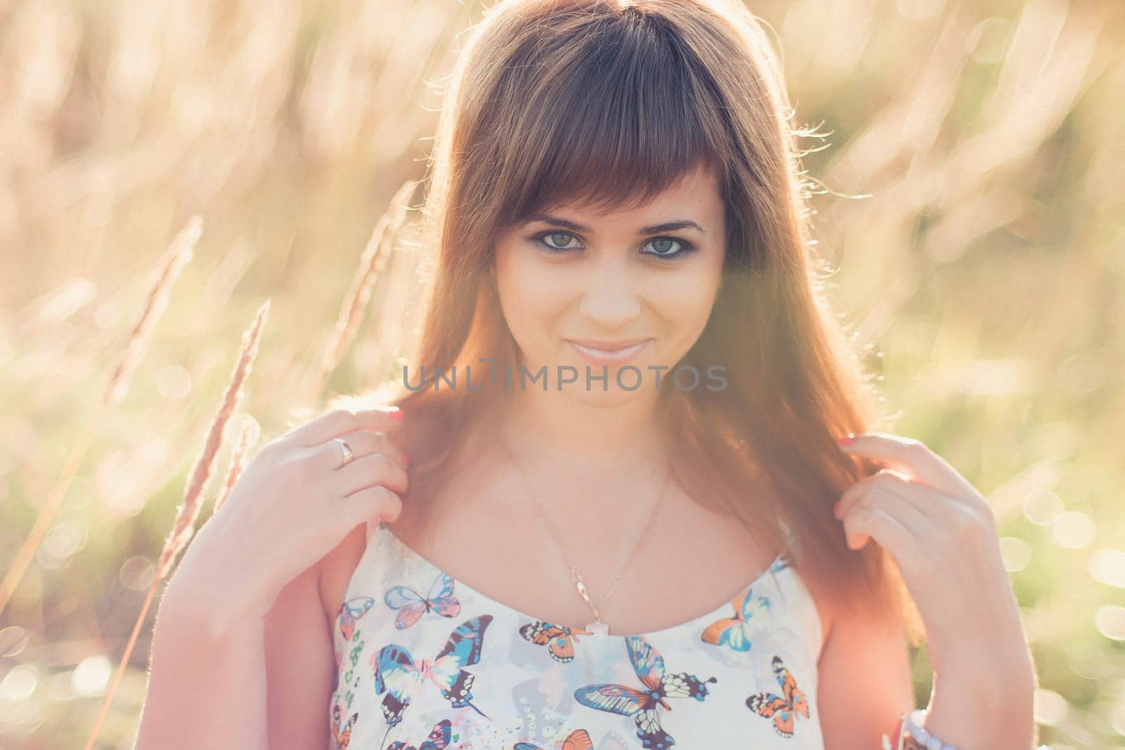 young Caucasian girl posing in summer at sunset in the field