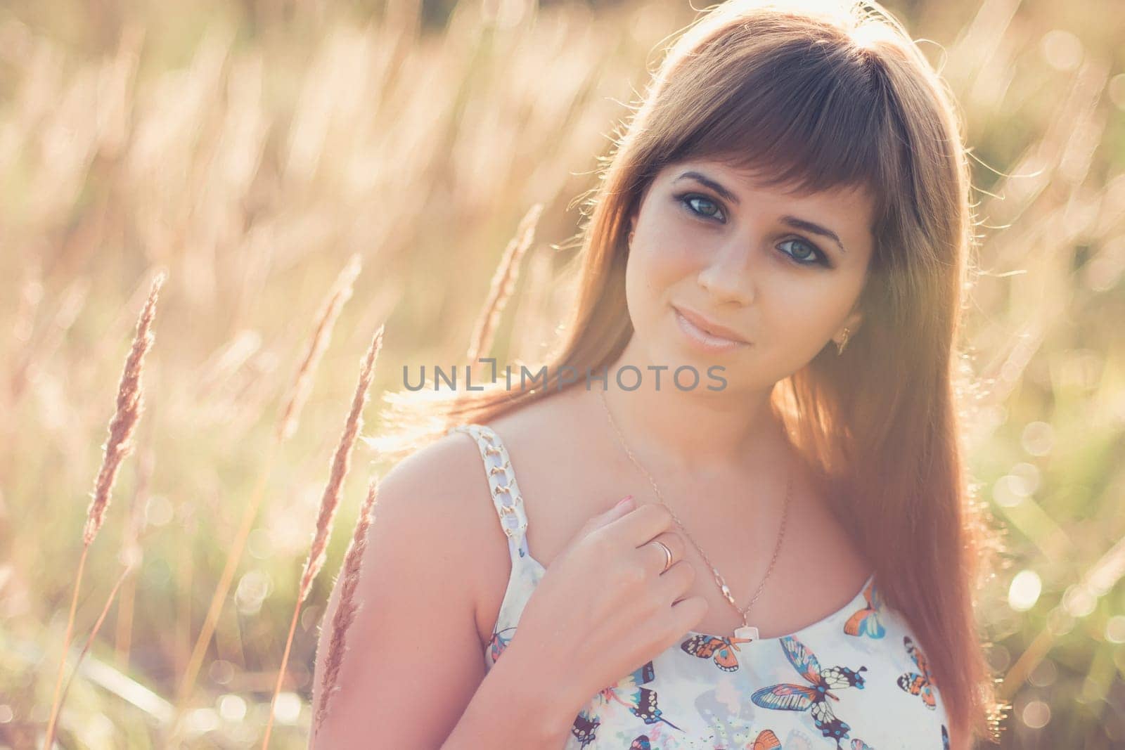 young Caucasian girl posing in summer at sunset in the field