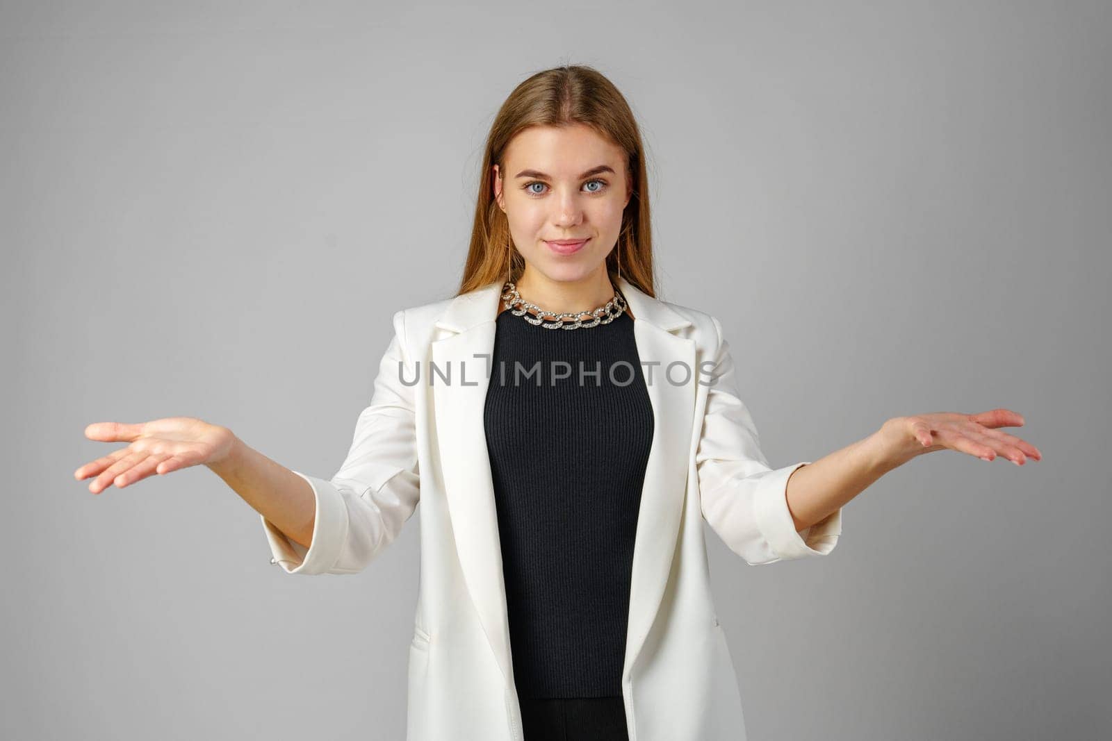 Young Woman Expressing Confusion With Hands Raised Against a Grey Background by Fabrikasimf