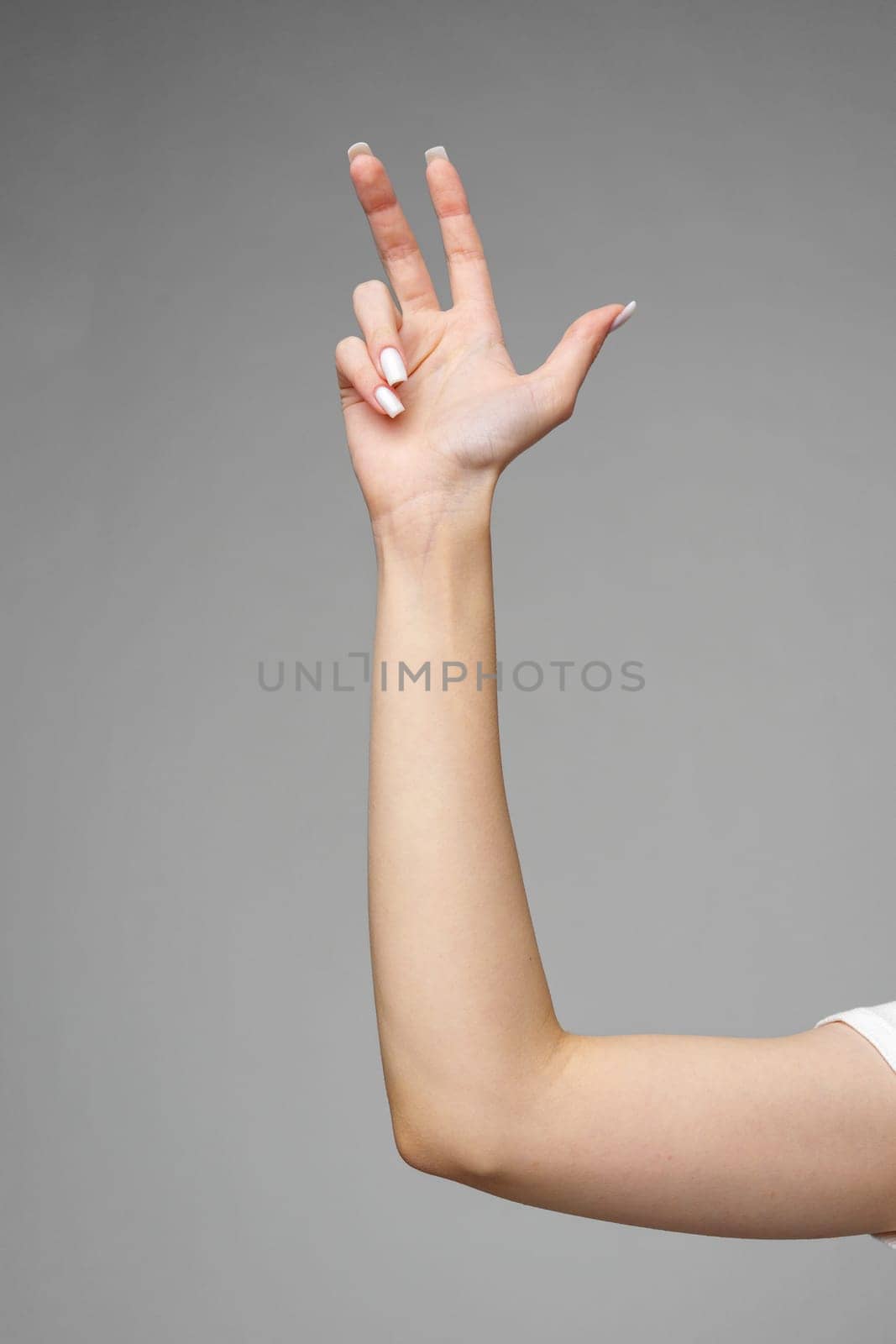 Female hand gesturing sign against gray background by Fabrikasimf