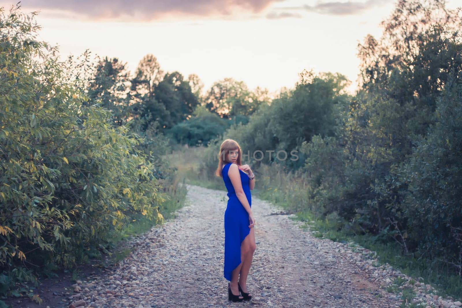 beautiful girl in blue dress posing on a background of sunset in nature