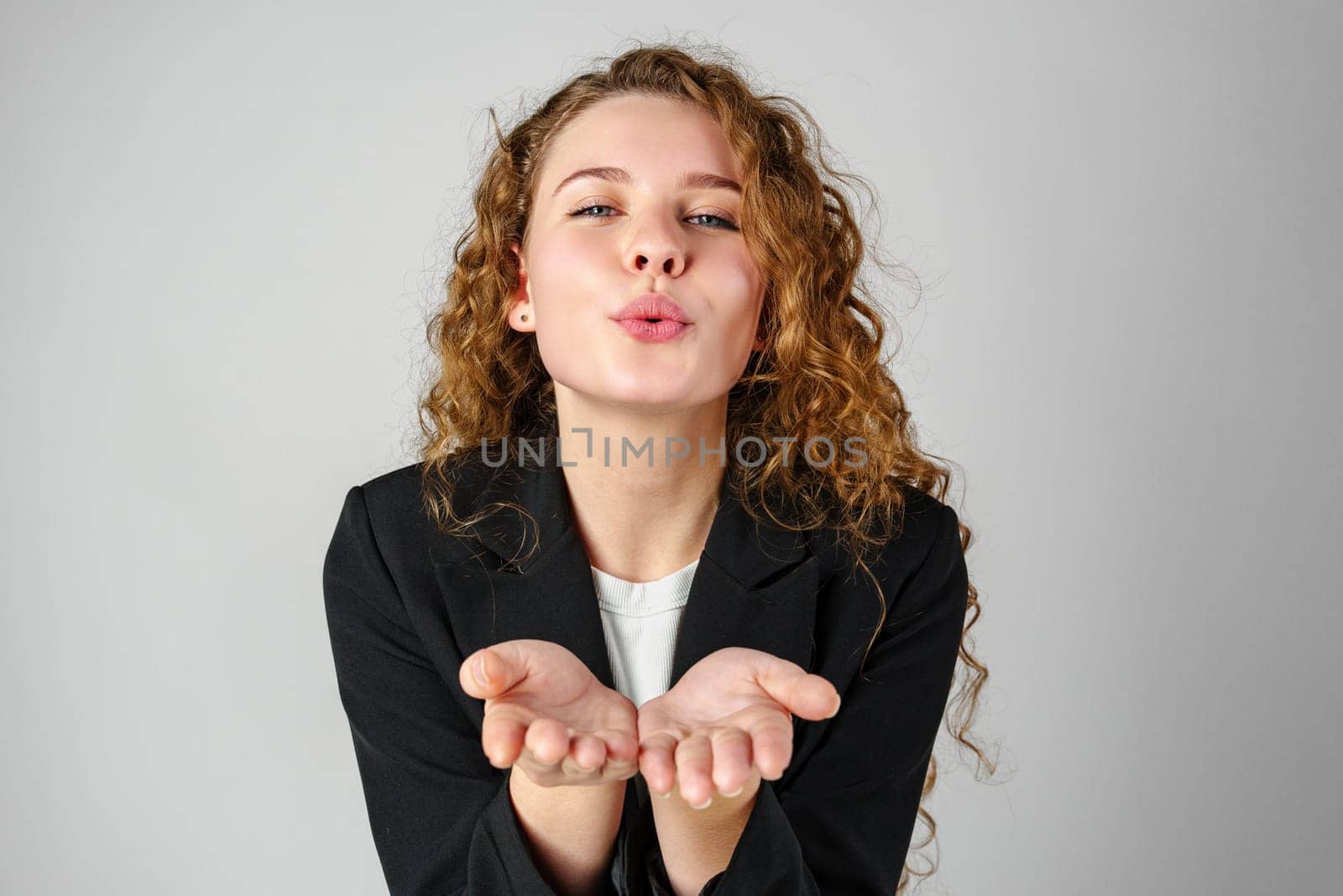 Young Woman Blowing a Kiss Towards the Camera in a Studio Setting by Fabrikasimf