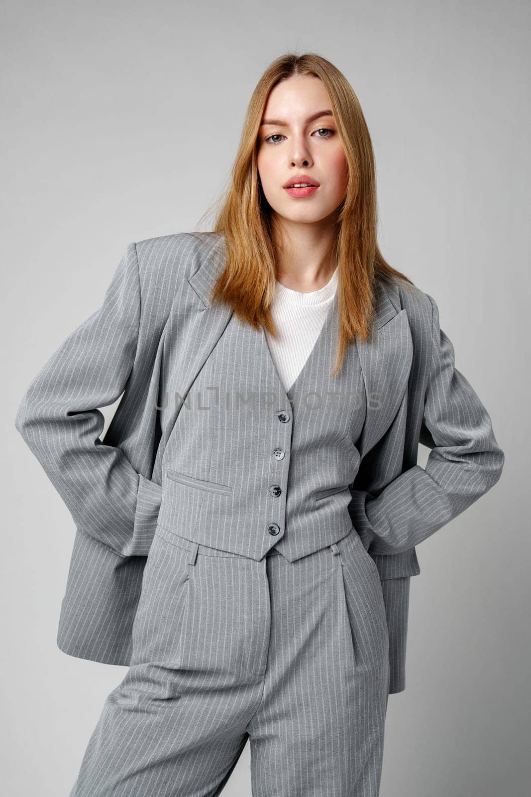 Woman in Gray Suit and White Shirt posing in studio on gray background