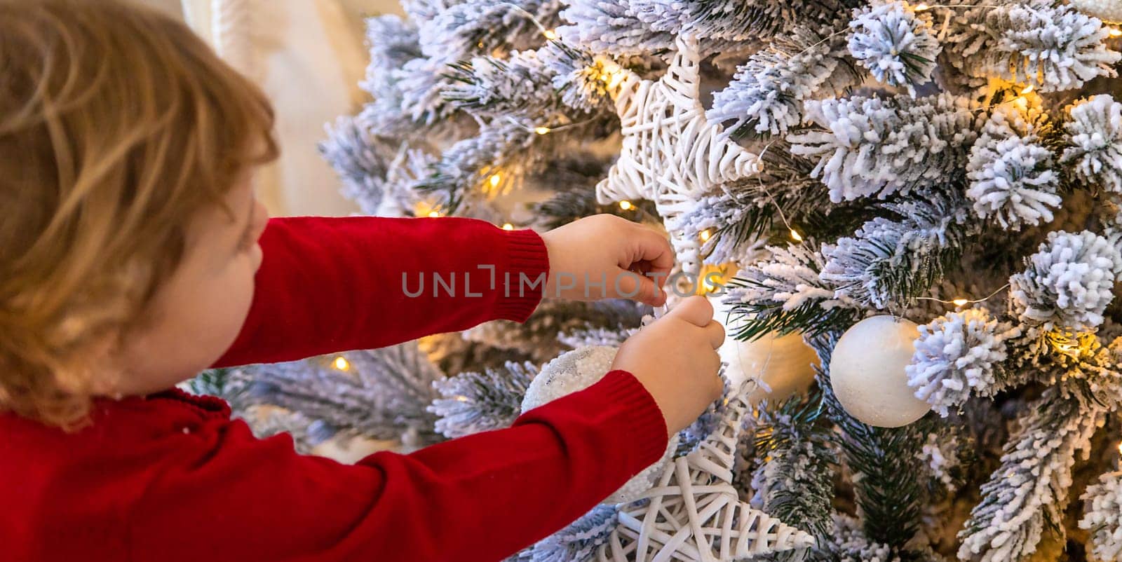 The child hangs a decoration on the Christmas tree. Selective focus. Kid.