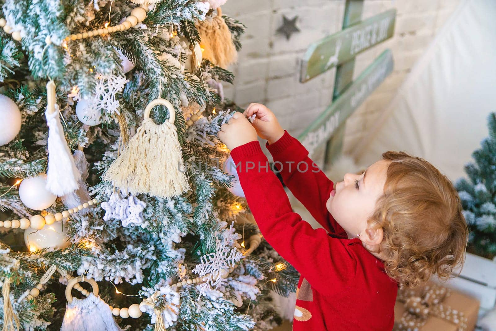 The child hangs a decoration on the Christmas tree. Selective focus. Kid.