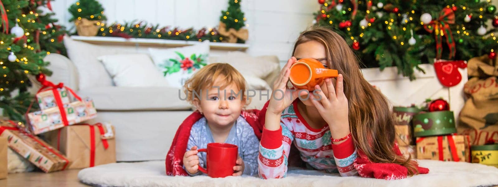 Children drink tea near the Christmas tree. Selective focus. Kid.