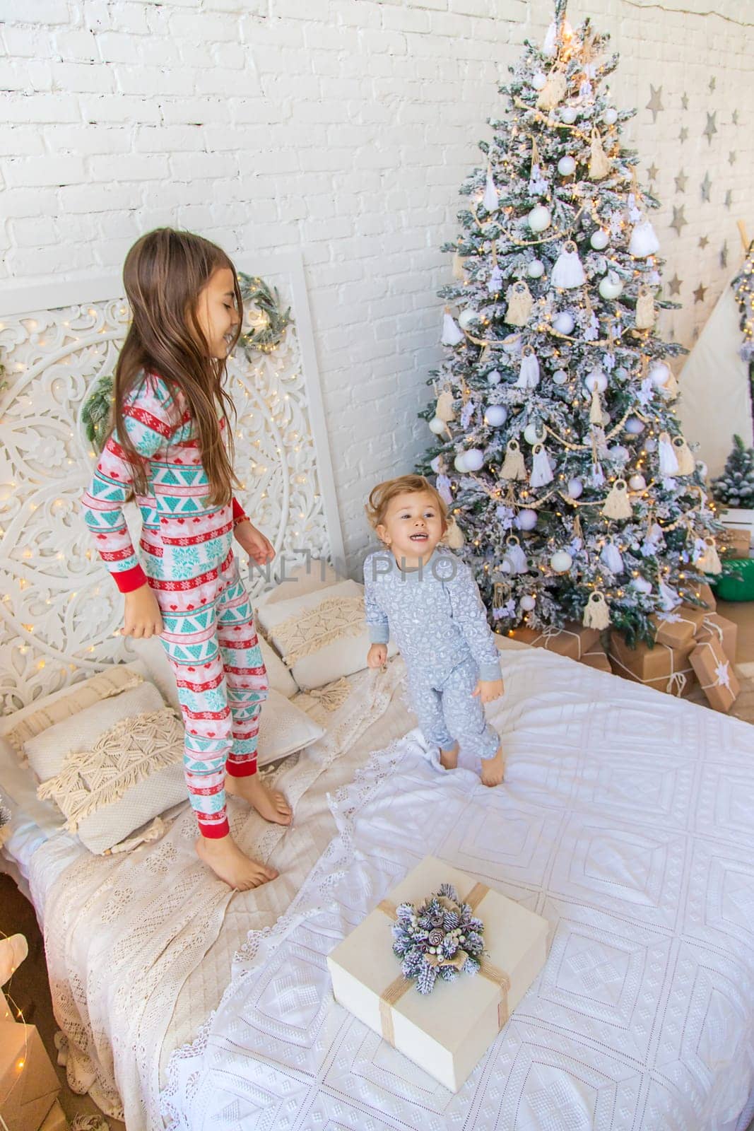 Children jump on the bed near the Christmas tree. Selective focus. kid.