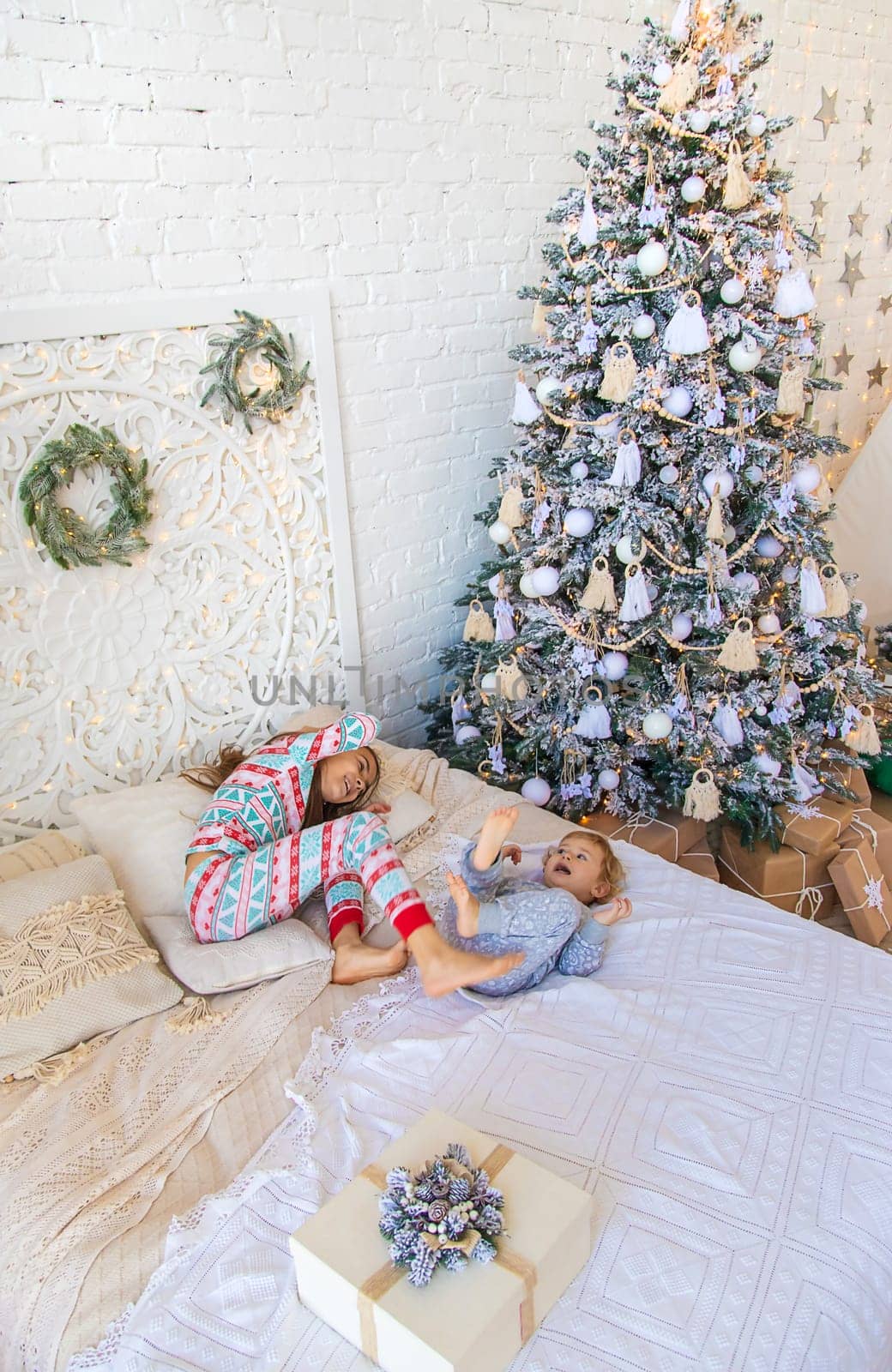 Children jump on the bed near the Christmas tree. Selective focus. kid.