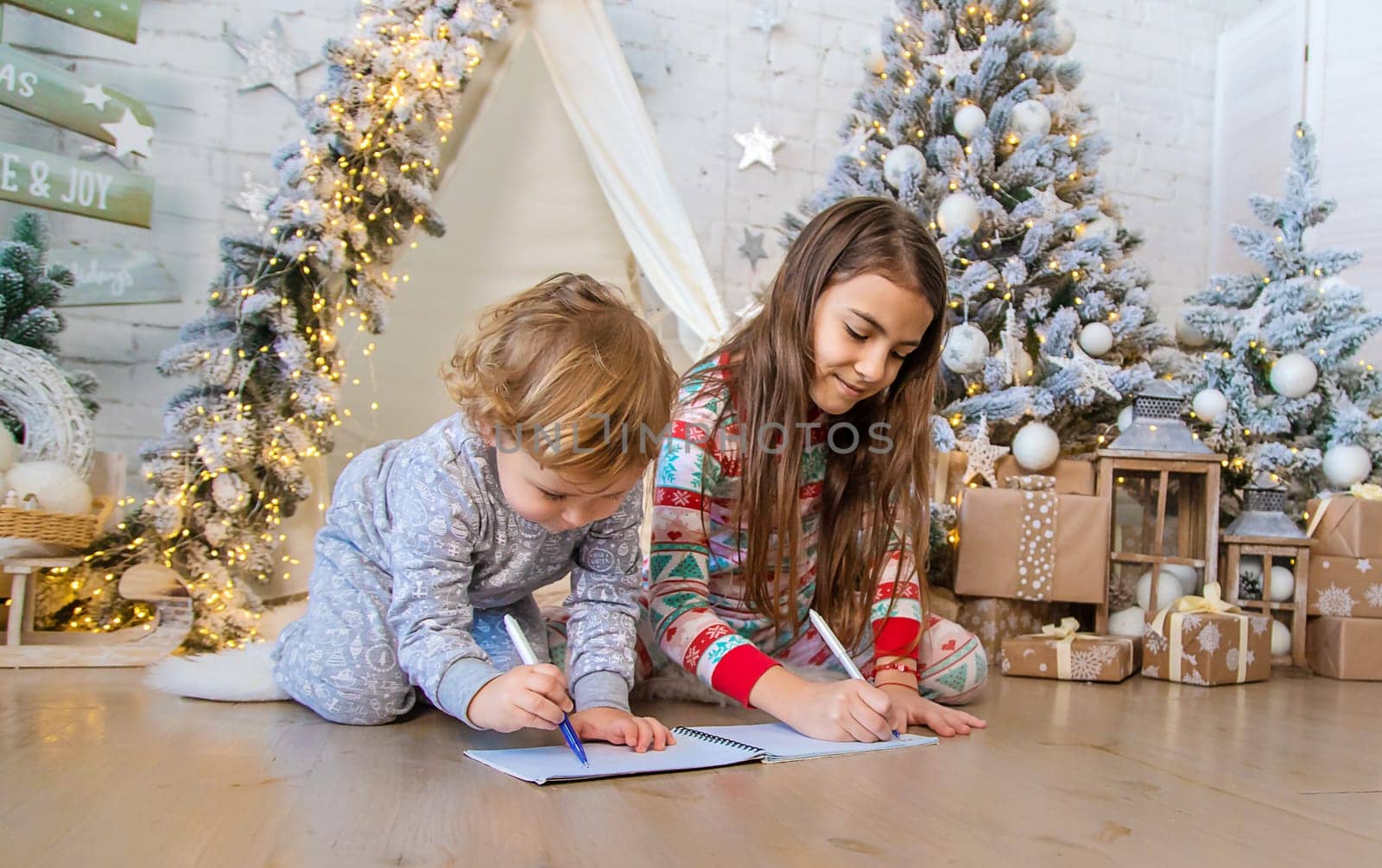 Children write a letter to Santa under the tree. Selective focus. Kid.