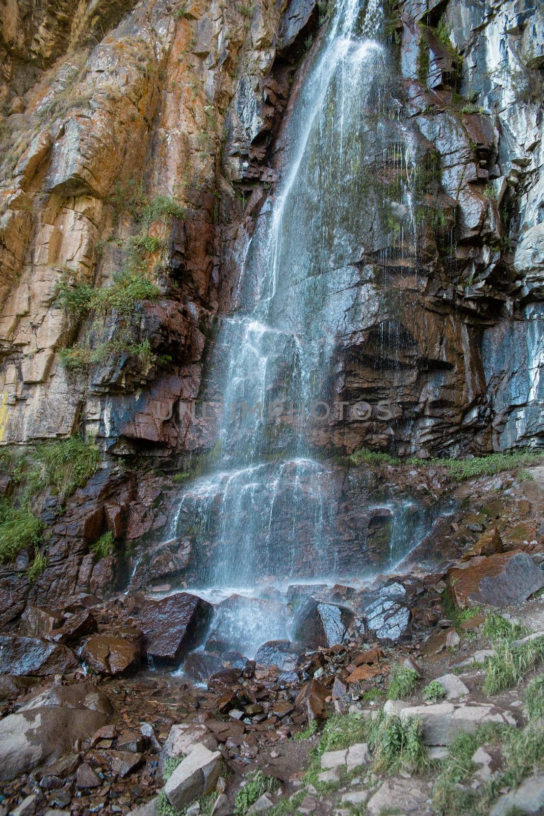 waterfall among rocks in a mountain stream. Water landscape surrounded by huge rocks in a summer forest