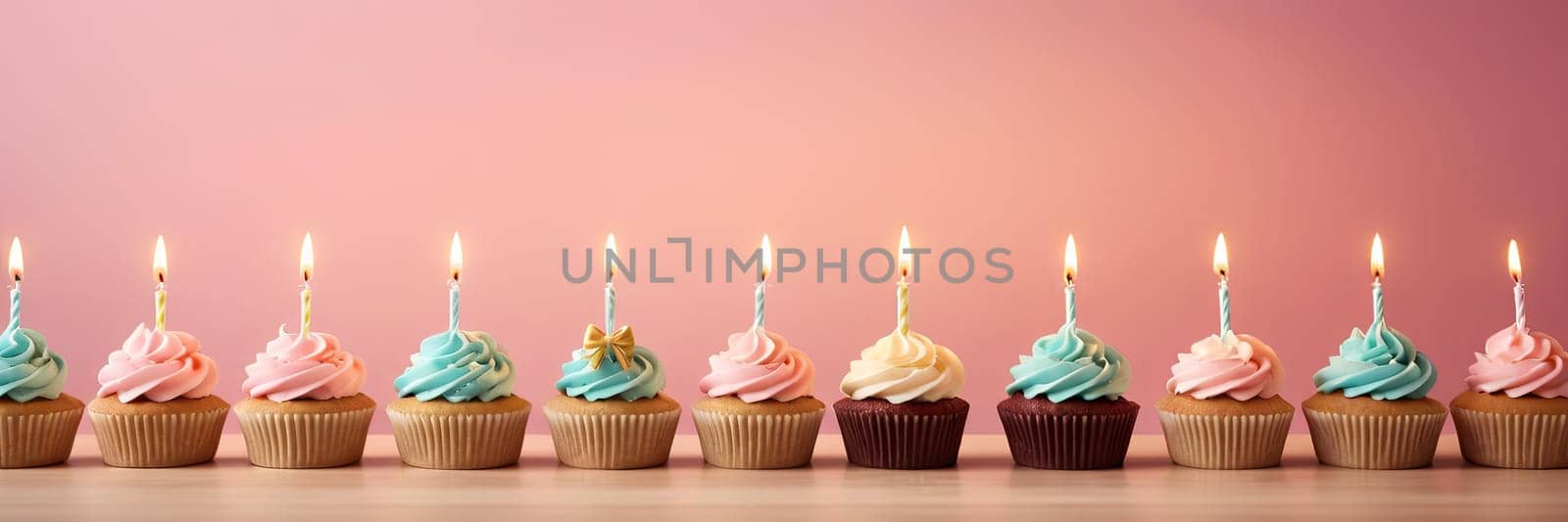 Colorful cupcakes with lit candles are displayed against a pink background, indicating an indoor celebration event marking of joy and celebrating. with free space by Matiunina